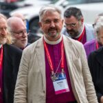 A group of male and female bishops walking outdoors.