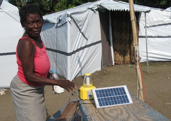 A woman uses a solar panel power source at a camp in Petite-Rivière, Haiti. Photo by Naba Gurung/PWRDF.