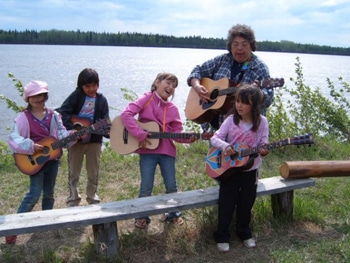 The Rev. Canon Ginny Doctor teaches kids to play bluegrass on the shores of the Yukon River, Tanana, Alaska.  THE REV. BELLE MICKELSON