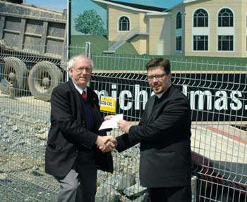 Archdeacon John Robertson presents Mr. Ash's gift to the Rev. Sam Rose on the site of the church's new home. KEVIN SMITH