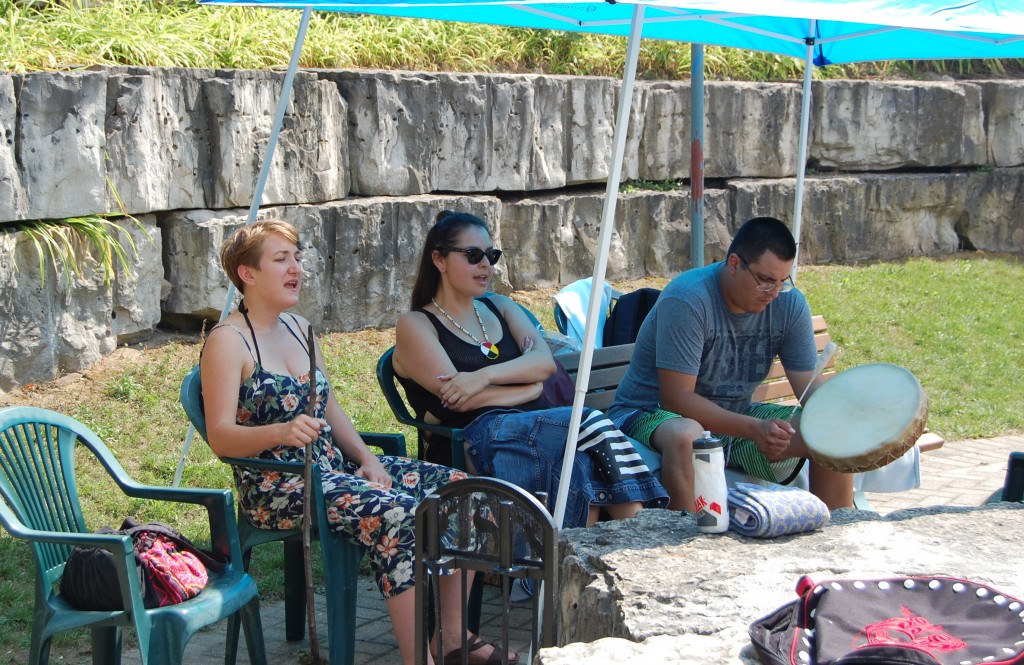 L-R: Leigh Kern and Danielle Black sing a traditional song by the Sacred Fire as Jesse Johns provides a drumbeat.