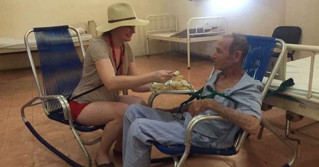 Justice Camp participant Alicia Archbell helps feed a resident at the Colony shelter.