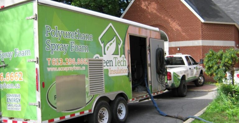 GreenTech trailer parked outside a building, featuring equipment for energy efficiency services, with hoses connected for operation.