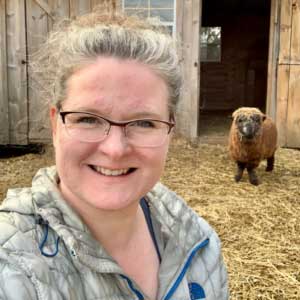 Selfie Photo of Keri Rose with sheep in the background.