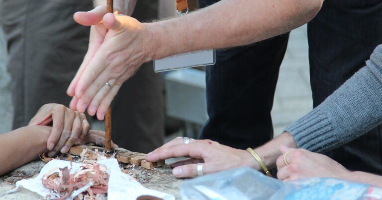 Hands engaged in a woodworking project, using tools and materials to create a piece of art. The focus is on the craftsmanship and collaboration involved in the process.
