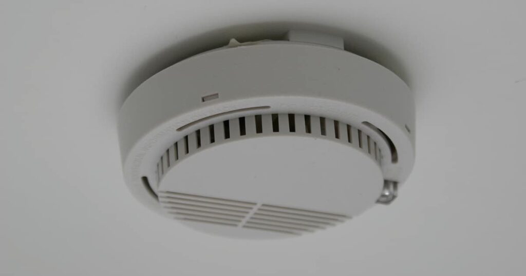 Smoke detector mounted on a ceiling, featuring a circular design with vents for smoke detection.