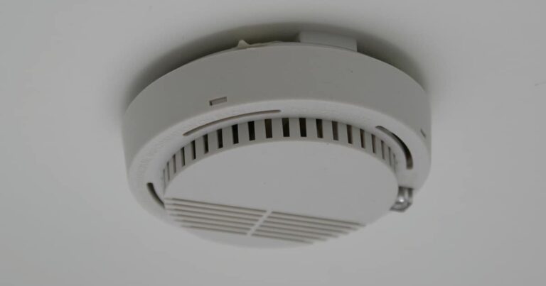 Smoke detector mounted on a ceiling, featuring a circular design with vents for smoke detection.