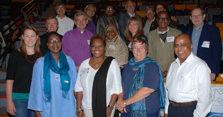 Group photo of diverse individuals smiling and posing together at an event, showcasing a range of backgrounds and attire.