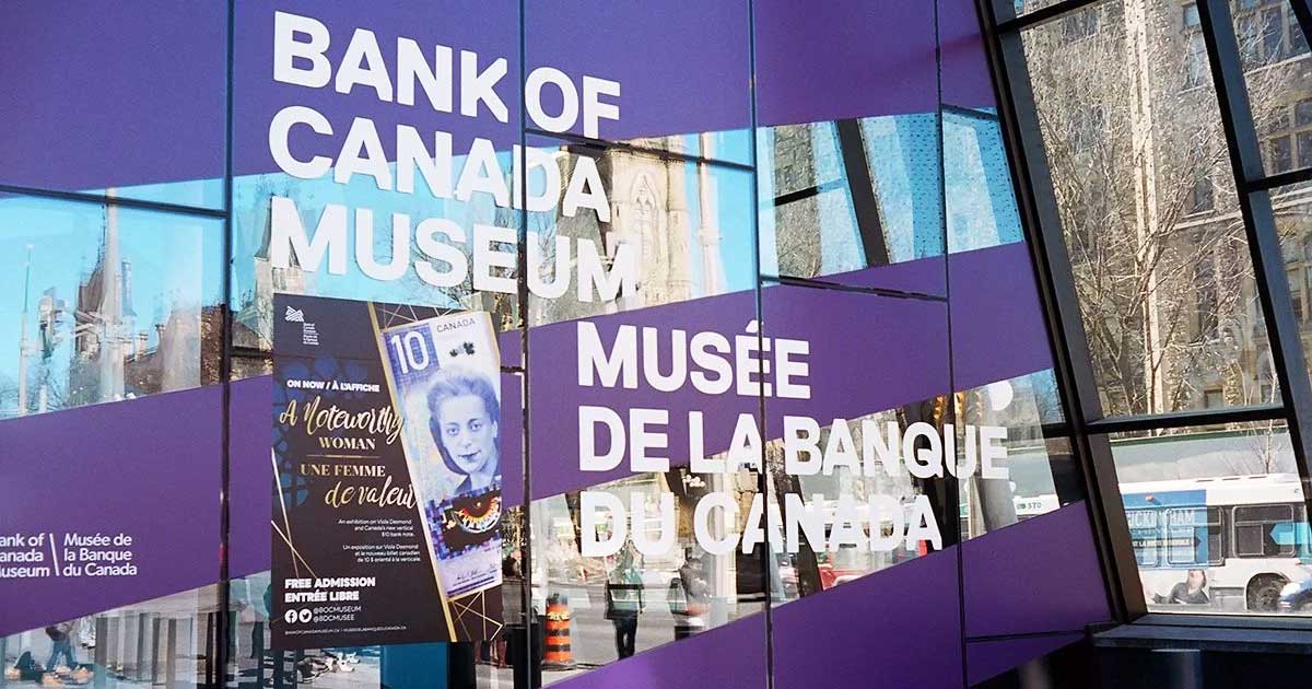 Photo of a purple covered window with the text 'BANK OF CANADA MUSEUM' and 'Musee de la Banque du Canada' below it, along with an image of a Canadian $10 bill.