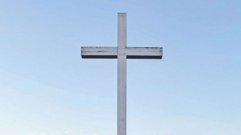 White wooden cross against a clear blue sky
