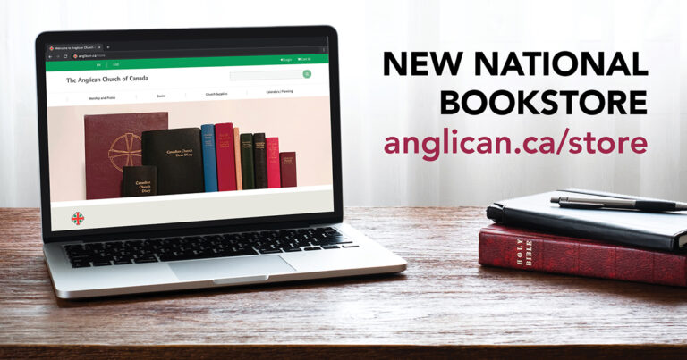 Laptop displaying a website for a new Anglican bookshop, featuring colorful book spines on a wooden table with a smartphone and additional books nearby.