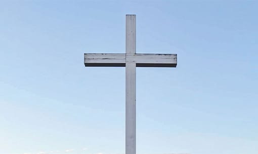 White wooden cross against a clear blue sky