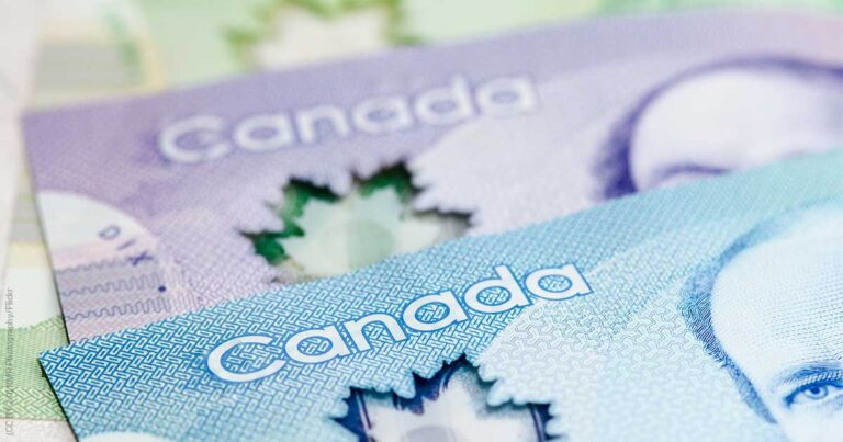 Close-up of Canadian banknotes featuring distinct colors and designs, highlighting the word "Canada" and the iconic maple leaf motif.