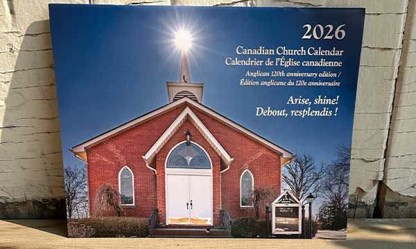 Cover of the 2026 Canadian Church Calendar featuring a red brick church with a white steeple and arched windows. Sunlight shines brightly from the top of the steeple against a clear blue sky. The text on the cover reads “2026 Canadian Church Calendar / Calendrier de l’Église canadienne – Anglican 120th anniversary edition / Édition anglicane du 120e anniversaire – Arise, shine! / Debout, resplendis!”