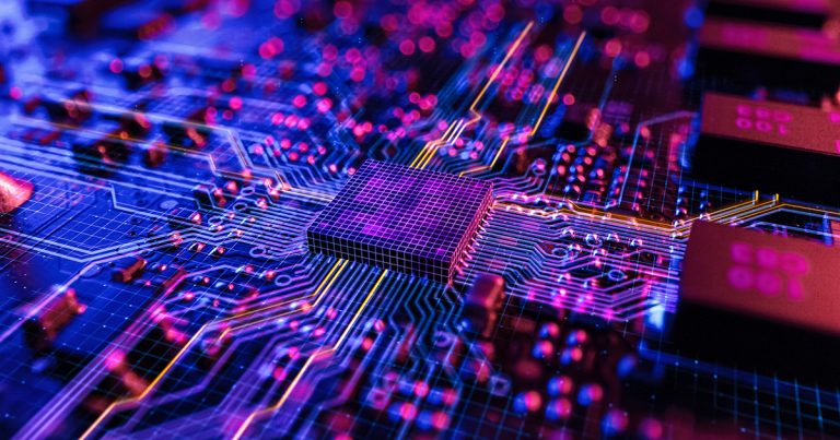 Close-up of a computer chip on a circuit board, glowing in vivid purple, blue, and magenta tones, with illuminated traces radiating outward and soft bokeh lights in the background.