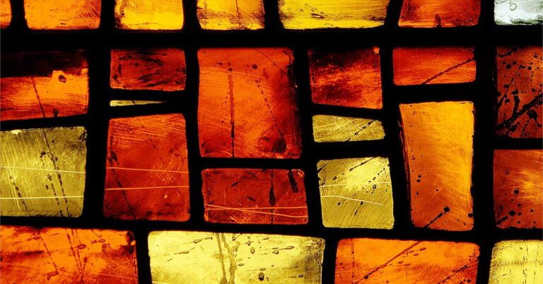 Abstract stained glass window featuring a mosaic of orange and yellow geometric shapes, creating a warm and vibrant pattern.