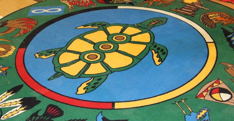 Colorful mural featuring a large green turtle with a yellow shell and three brown spots, surrounded by a circular blue background. The turtle is part of a vibrant design that includes various animal motifs.